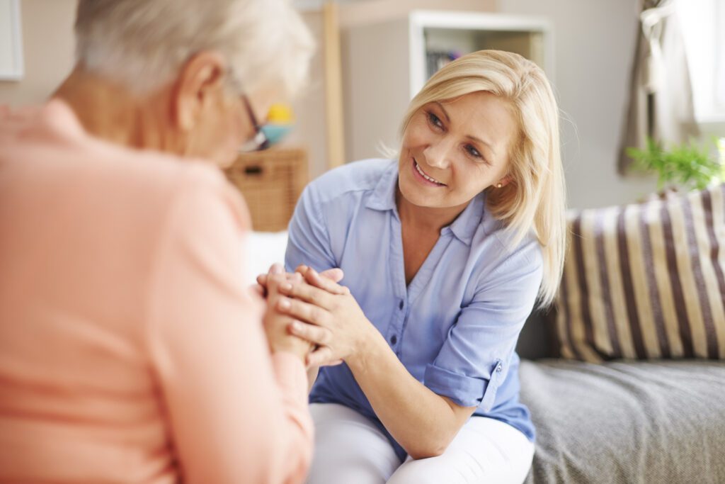 image of younger lady holding hands with an elderly woman